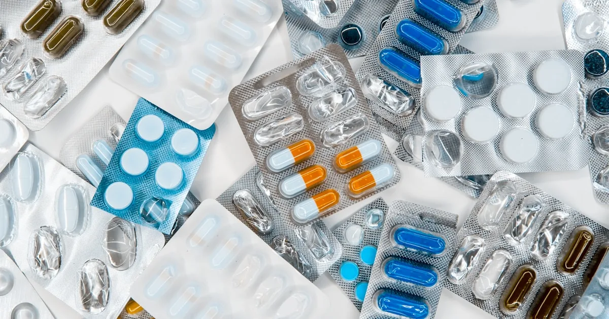Stacks of blister-packed tablets and capsules, representing batch volume