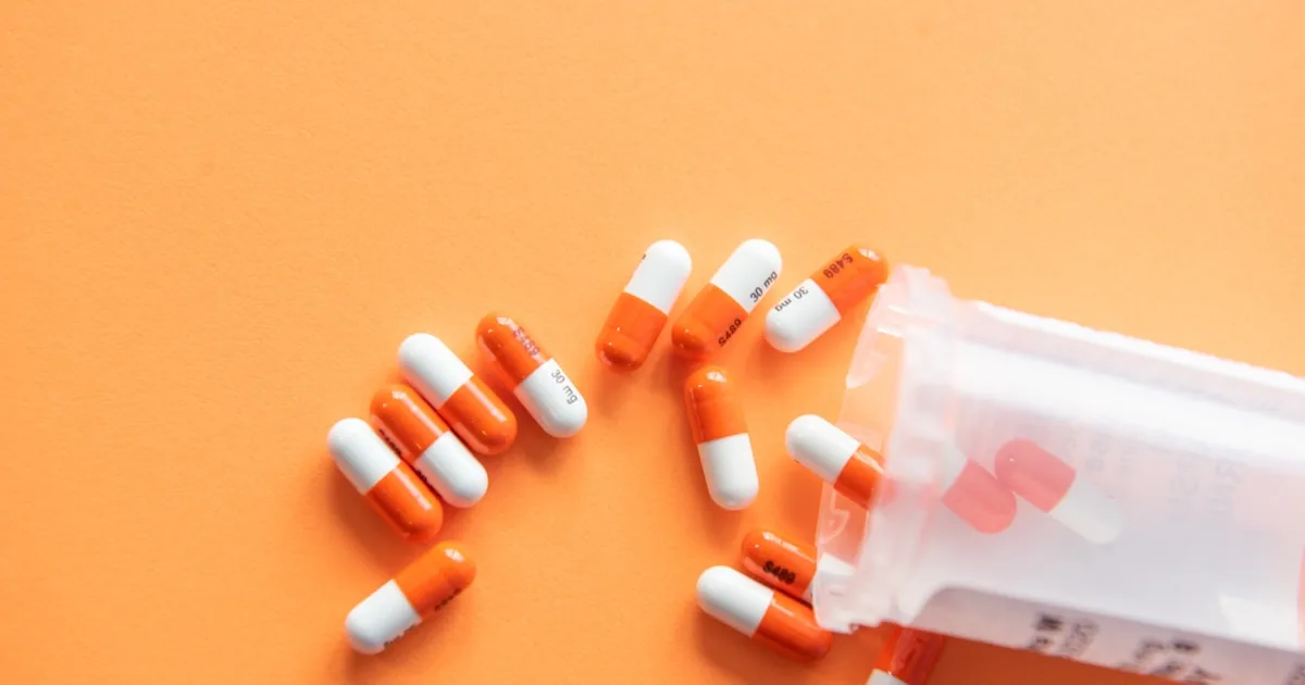 Orange capsules spilling from a bottle, ready for launch
